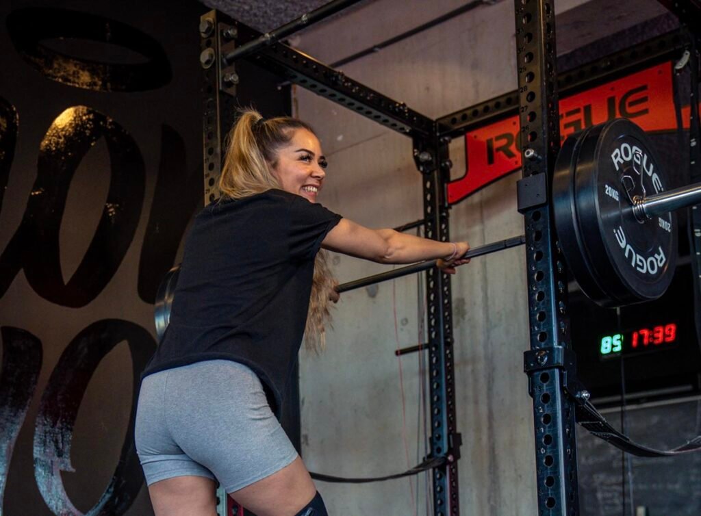 Sporter schuift een geladen barbell terug in het power rack en lacht richting camera. Sporter schuift een geladen barbell terug in het power rack en lacht richting camera.
